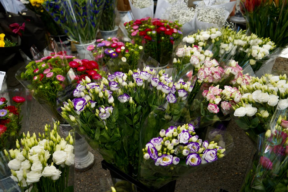 A display of fresh floral bouquets featuring a variety of flowers, including purple and white lisianthus, pink and white roses, and small daisies in shades of pink and purple. The flowers are arranged